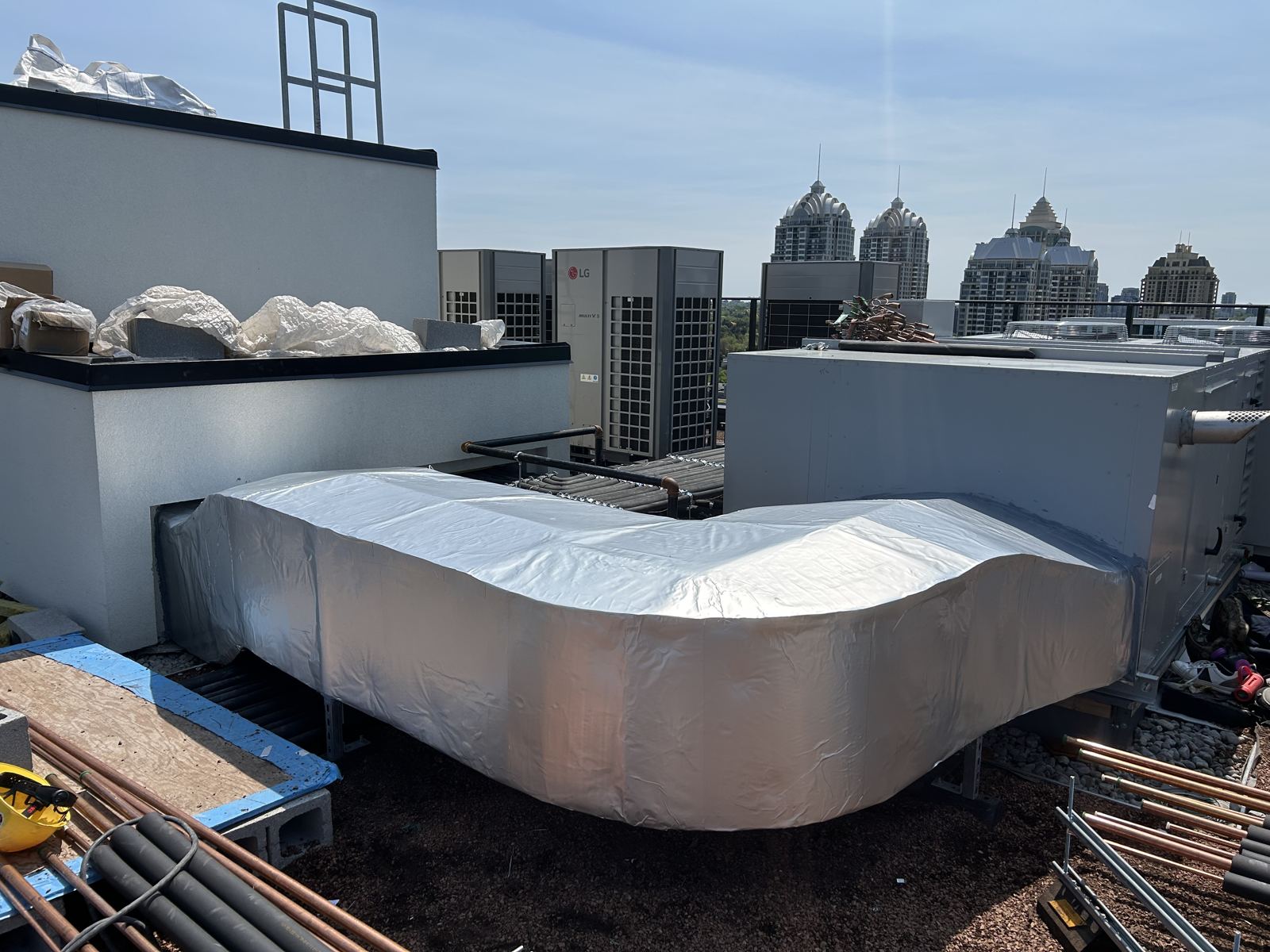 Rooftop supply duct wrapped and weather jacketed, Toronto skyline behind